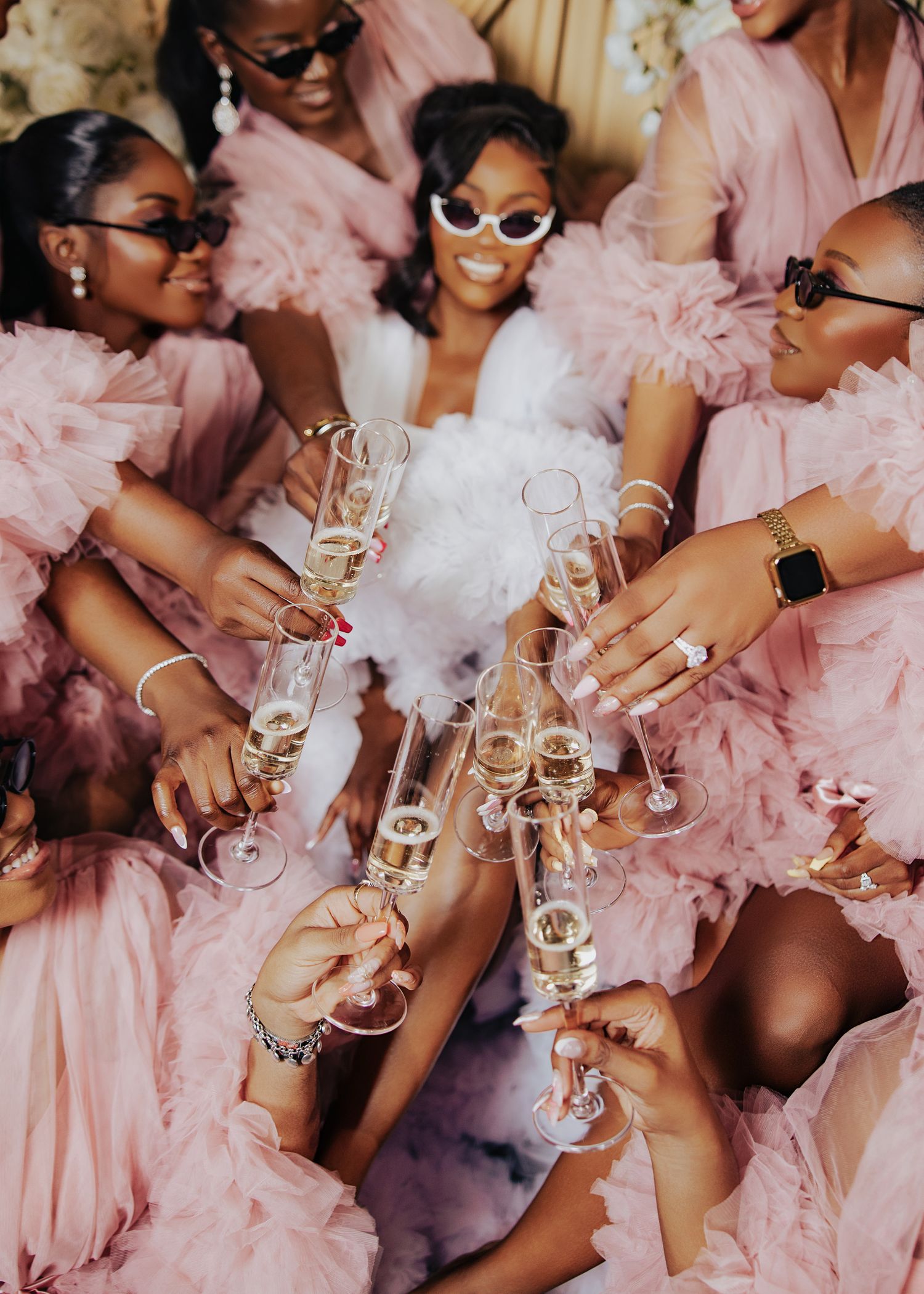 Wedding party in pink dresses toasting with champagne glasses during celebration.