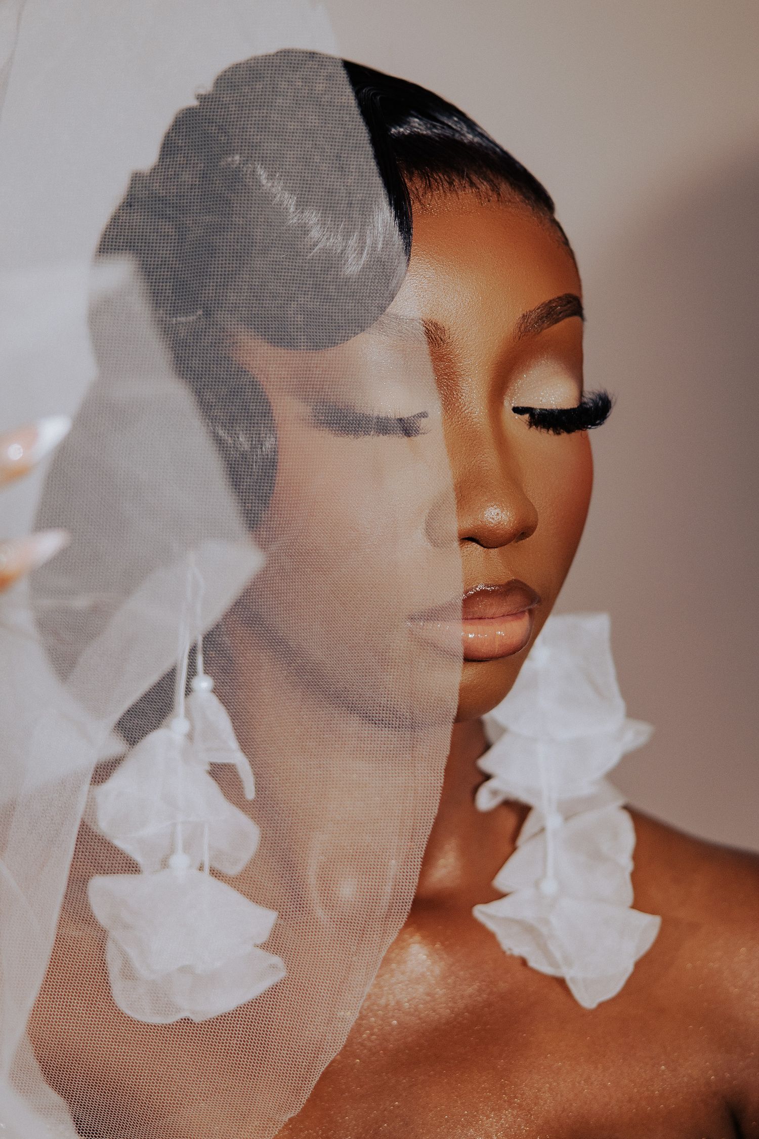 Close-up artistic bridal portrait with delicate white veil and soft lighting creating a dreamy effect.