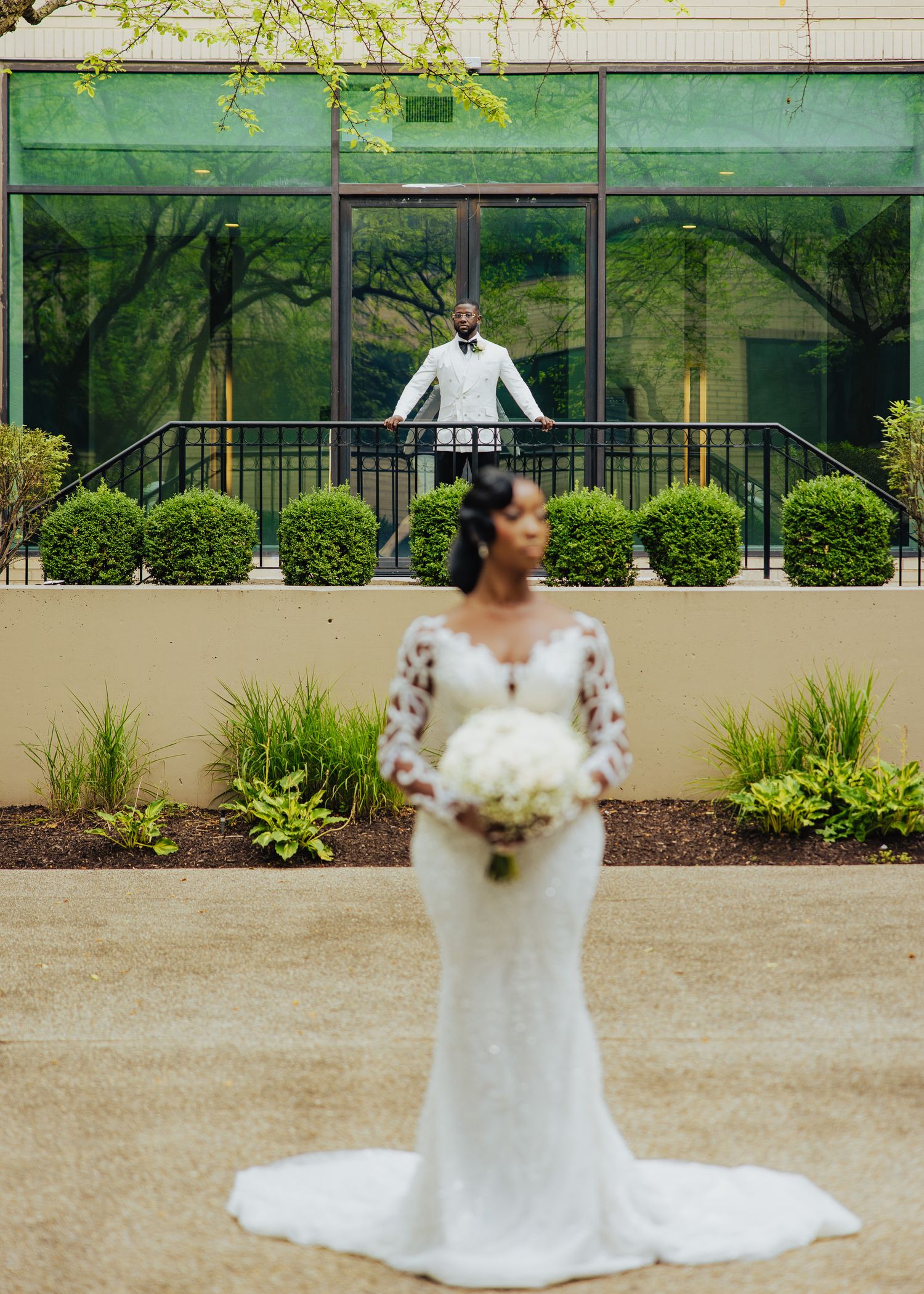 Wedding portrait with bride in foreground and reflection in glass building behind.