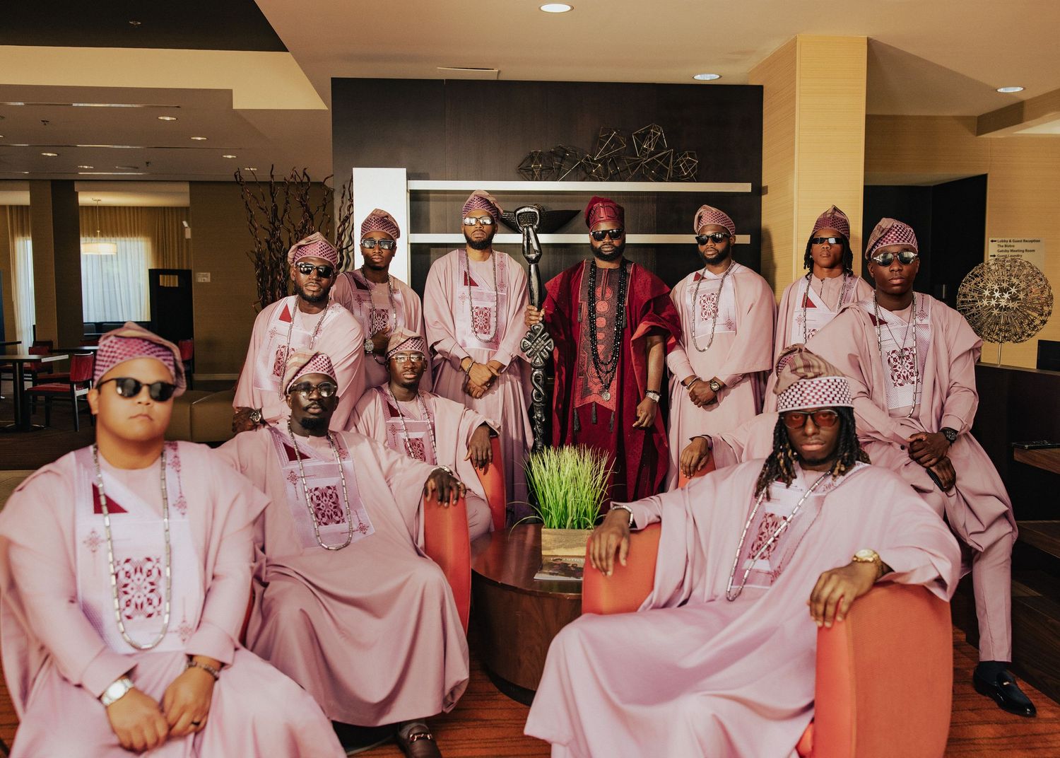 Large group wearing matching pink outfits gathered in indoor venue.