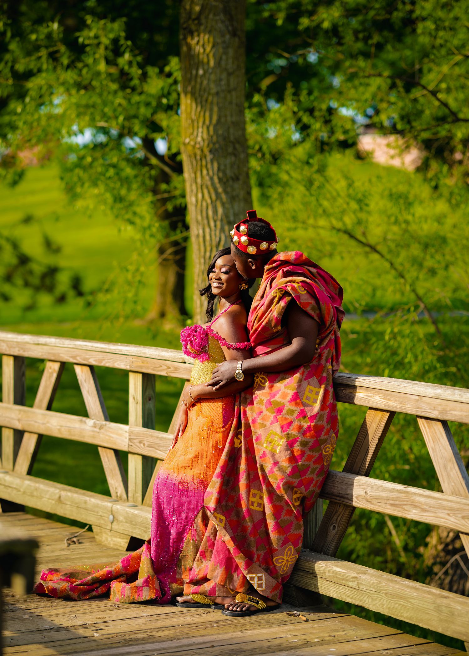 Bright floral dresses add pops of color against natural greenery on a wooden footbridge.