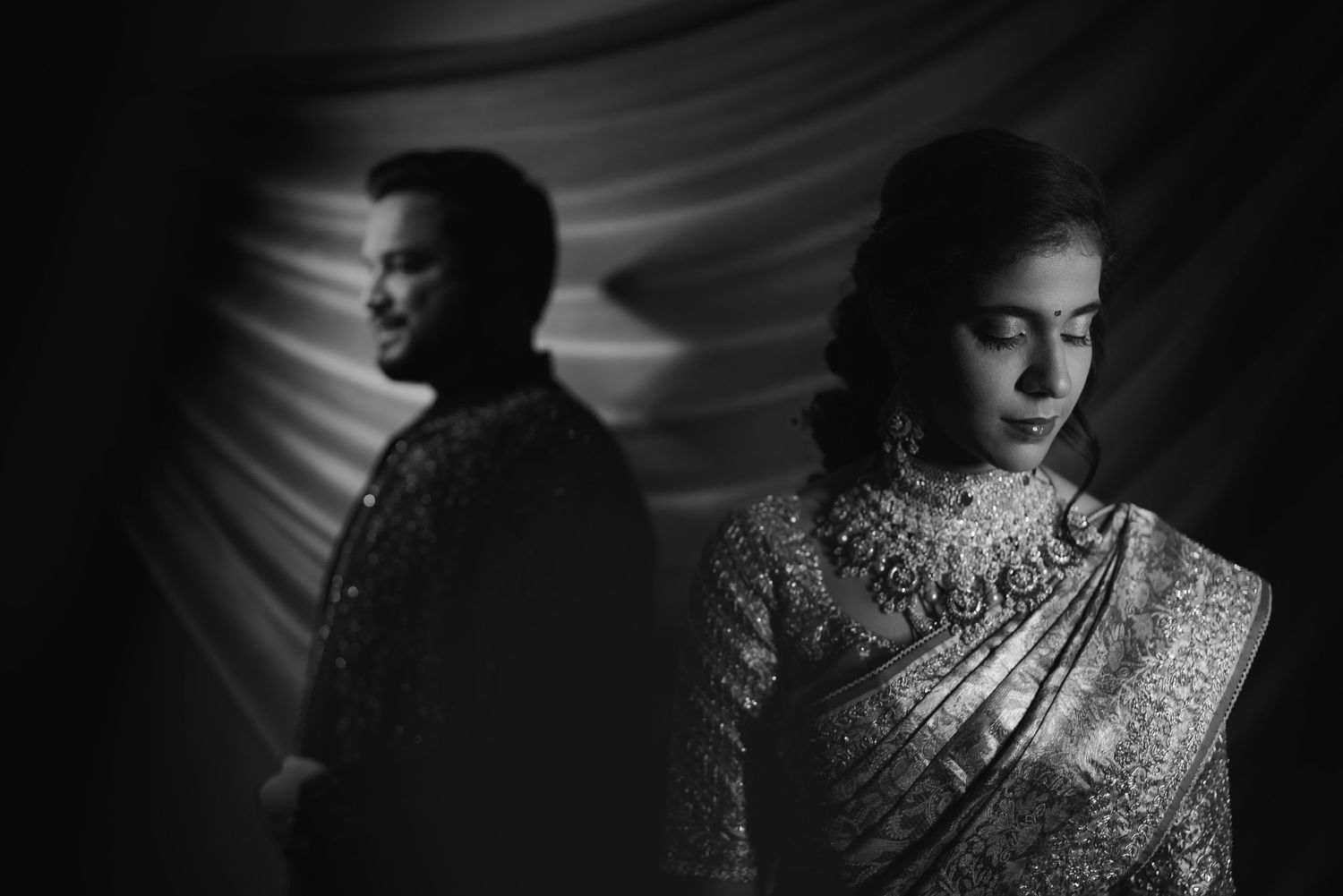 A dramatic black and white portrait showing contrasting emotions in traditional Indian attire.