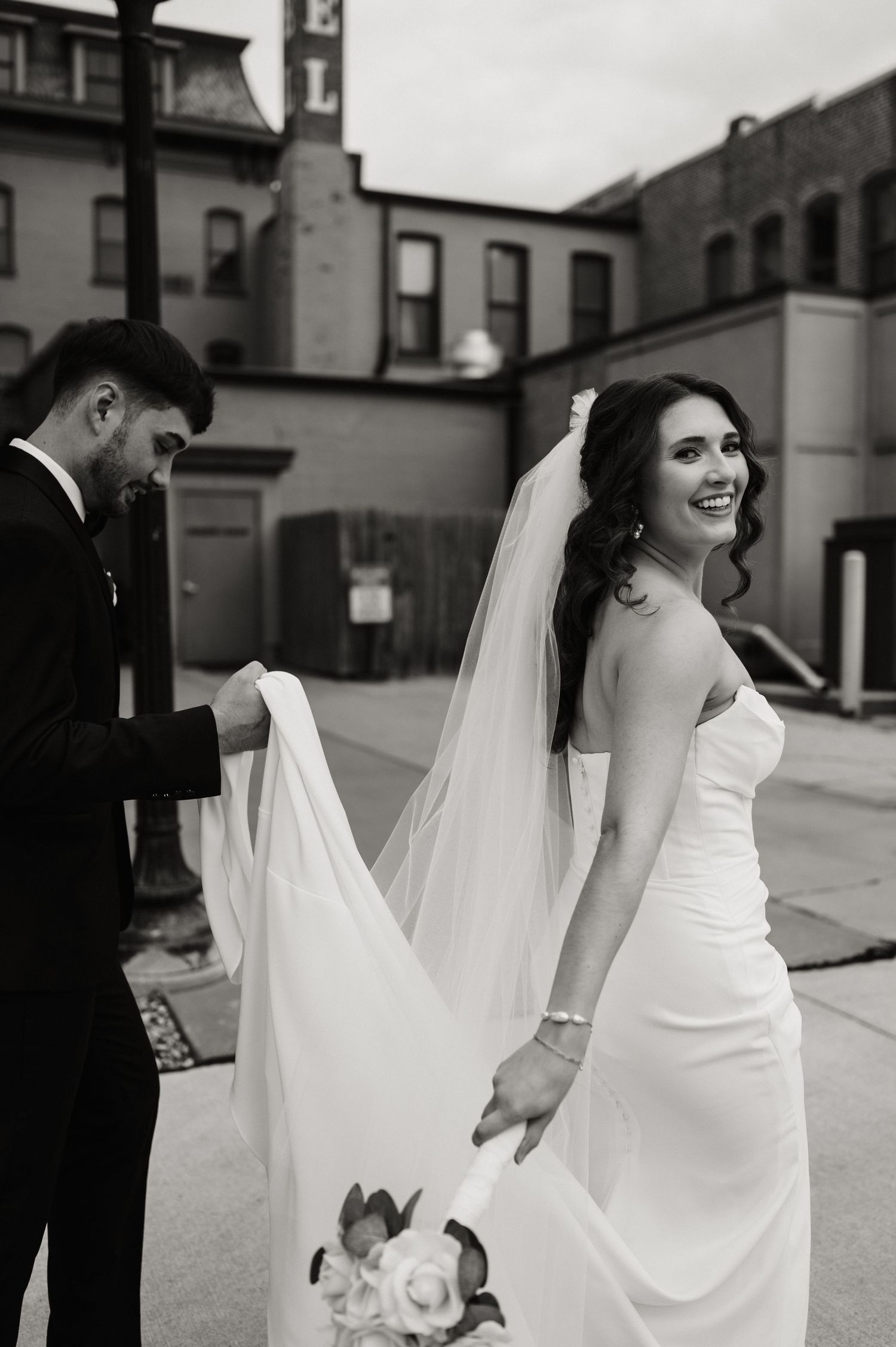 Couple embracing in a modern parking structure with geometric white ceiling patterns.