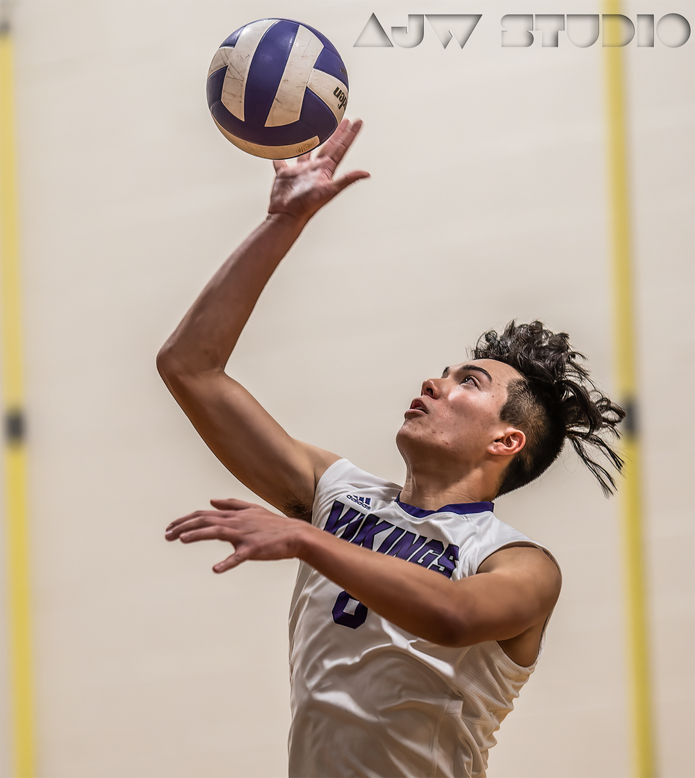 Volleyball player in white uniform preparing to set the ball during an indoor game.
