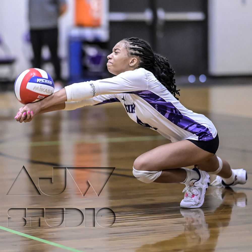 Volleyball player diving to save a ball during an indoor match.