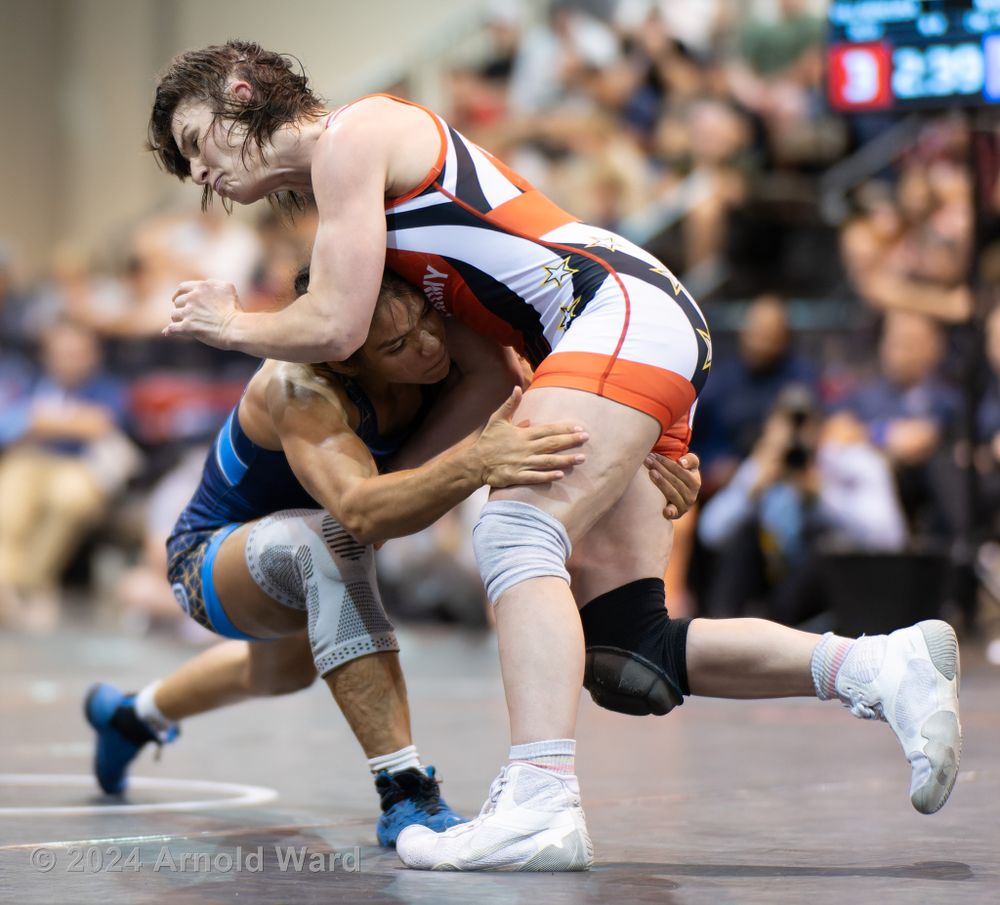 Two wrestlers compete in a match, one executing a takedown move on the other during an intense competition.