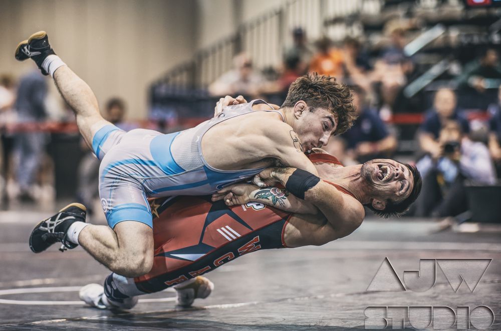 Two wrestlers locked in a dynamic grappling position during an intense match.