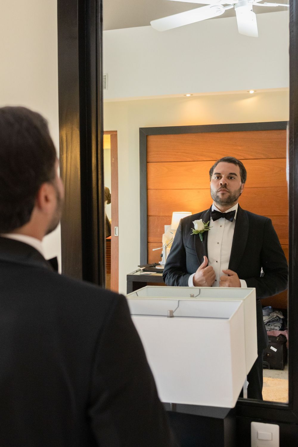 Reflections of a person in formal attire shown through multiple mirror panels in an interior space.