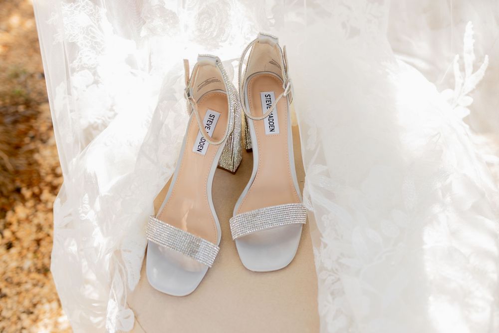 Elegant silver bridal shoes placed on white fabric against a golden autumn background.