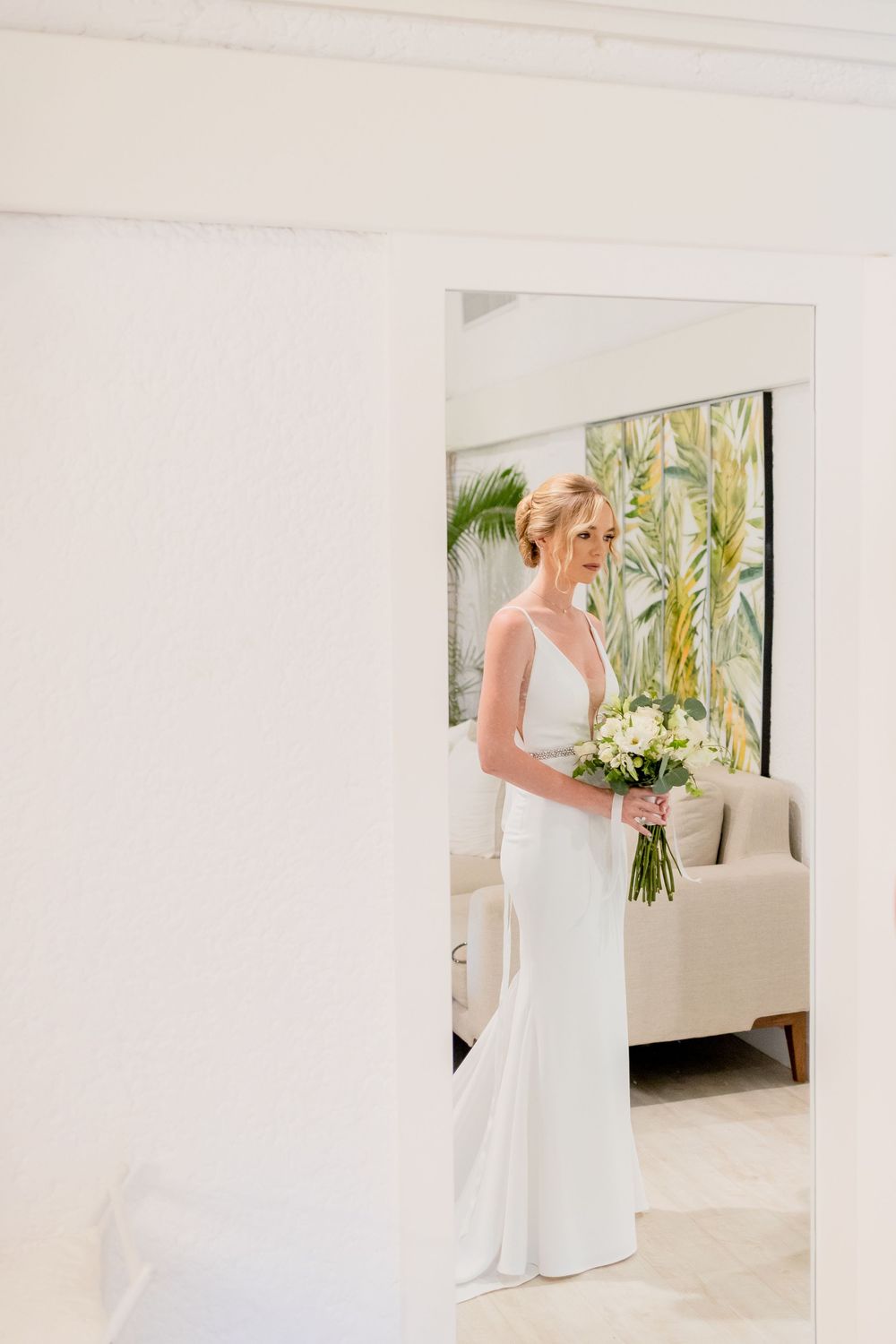 Elegant white wedding dress displayed in bright modern interior space.