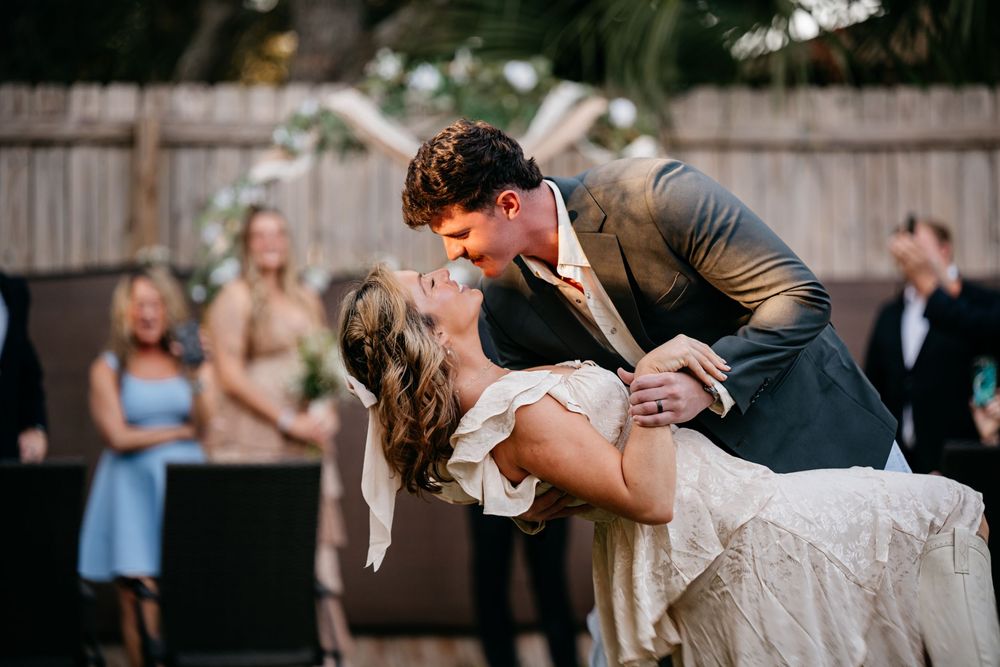 Dancing couple in casual attire enjoying a lively moment in an outdoor garden setting.