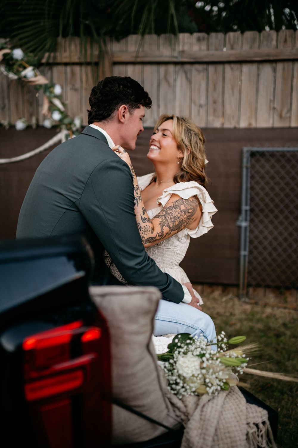 Romantic dance dip pose captured in a backyard setting with wooden fence backdrop.
