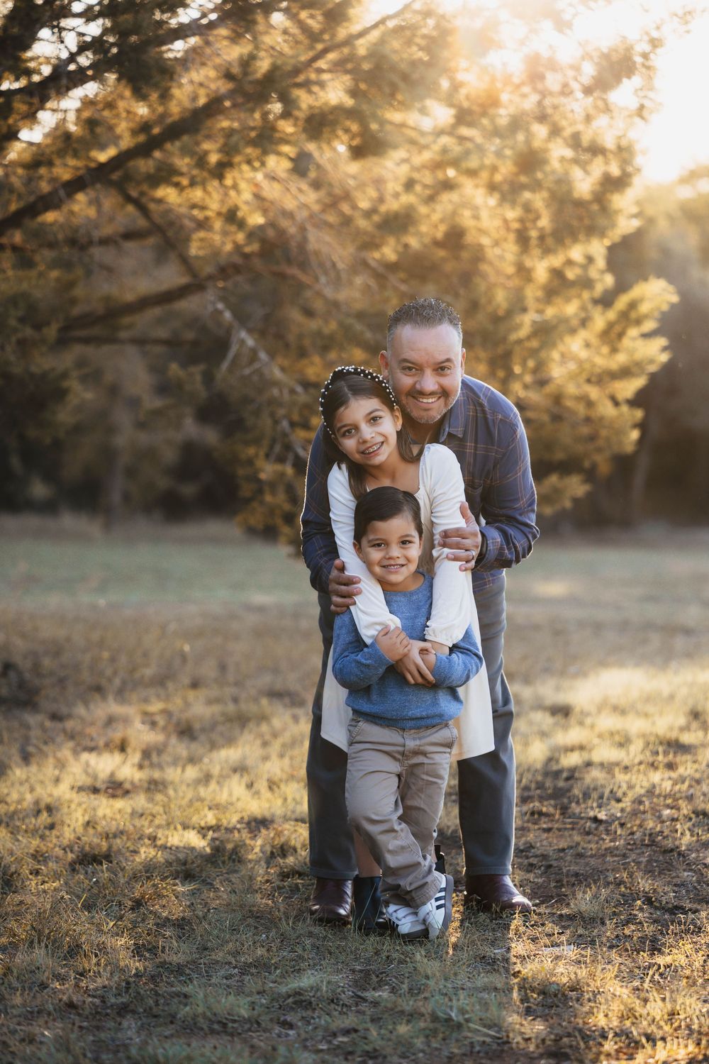 Candid family moments captured in golden sunlight during outdoor photo session at sunset.