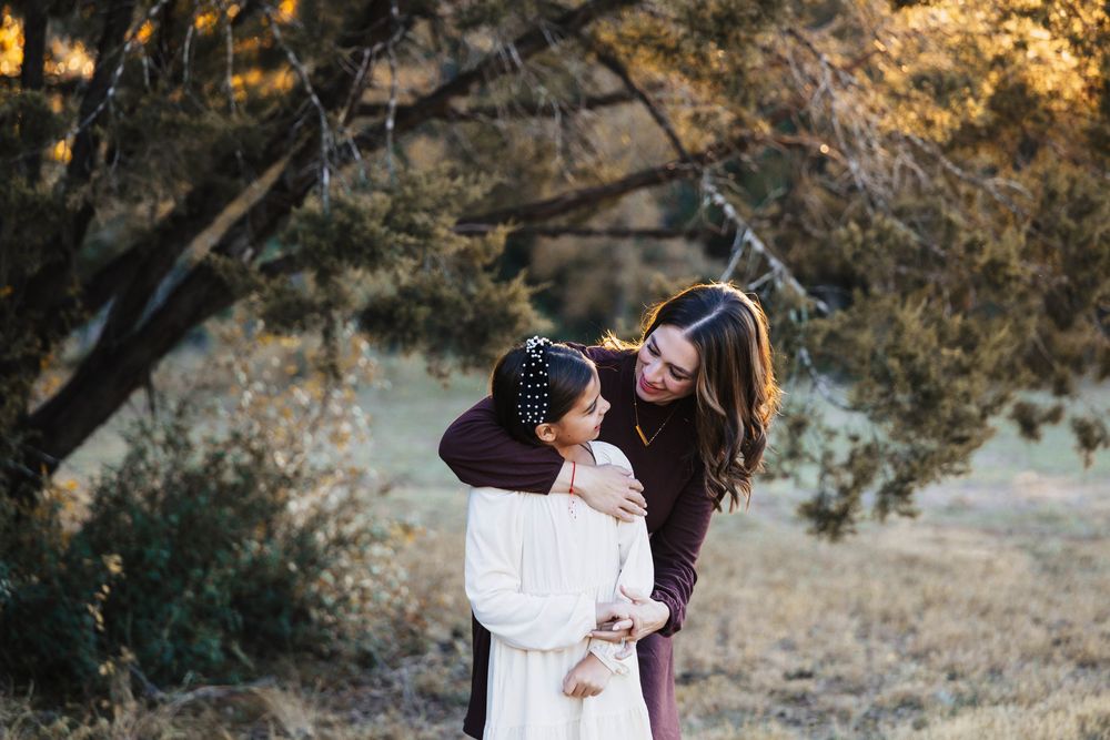 A couple embraces in a romantic moment during sunset in a golden-lit outdoor setting.