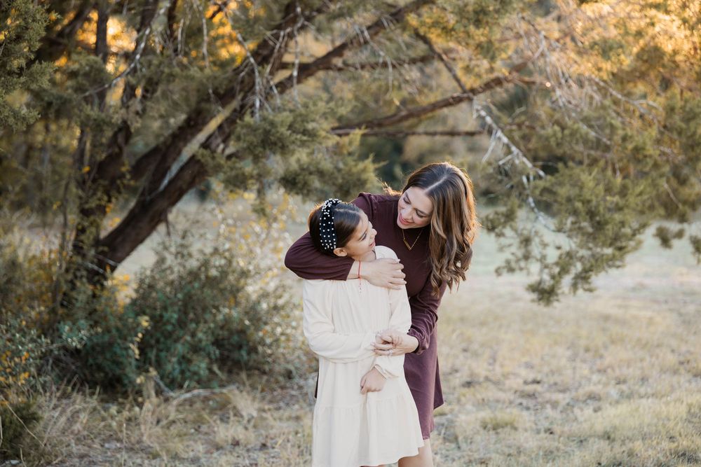 A couple embraces under autumn trees during a romantic outdoor photoshoot at golden hour.