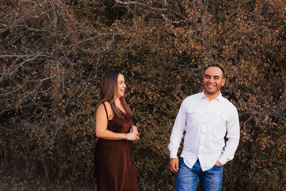 Family portrait session at sunset with warm autumn colors and rustic brown foliage in the background.