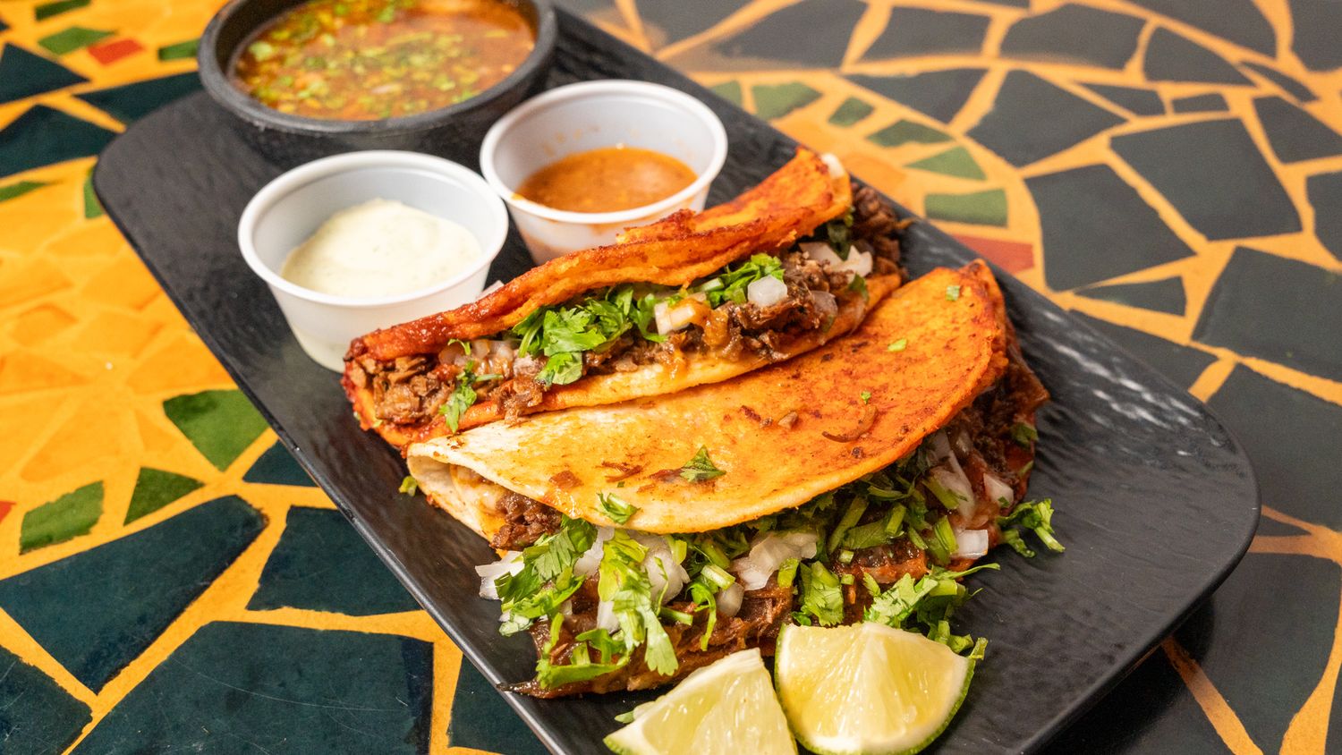 Close-up shots of gourmet sandwiches and dips on black slate serving boards.
