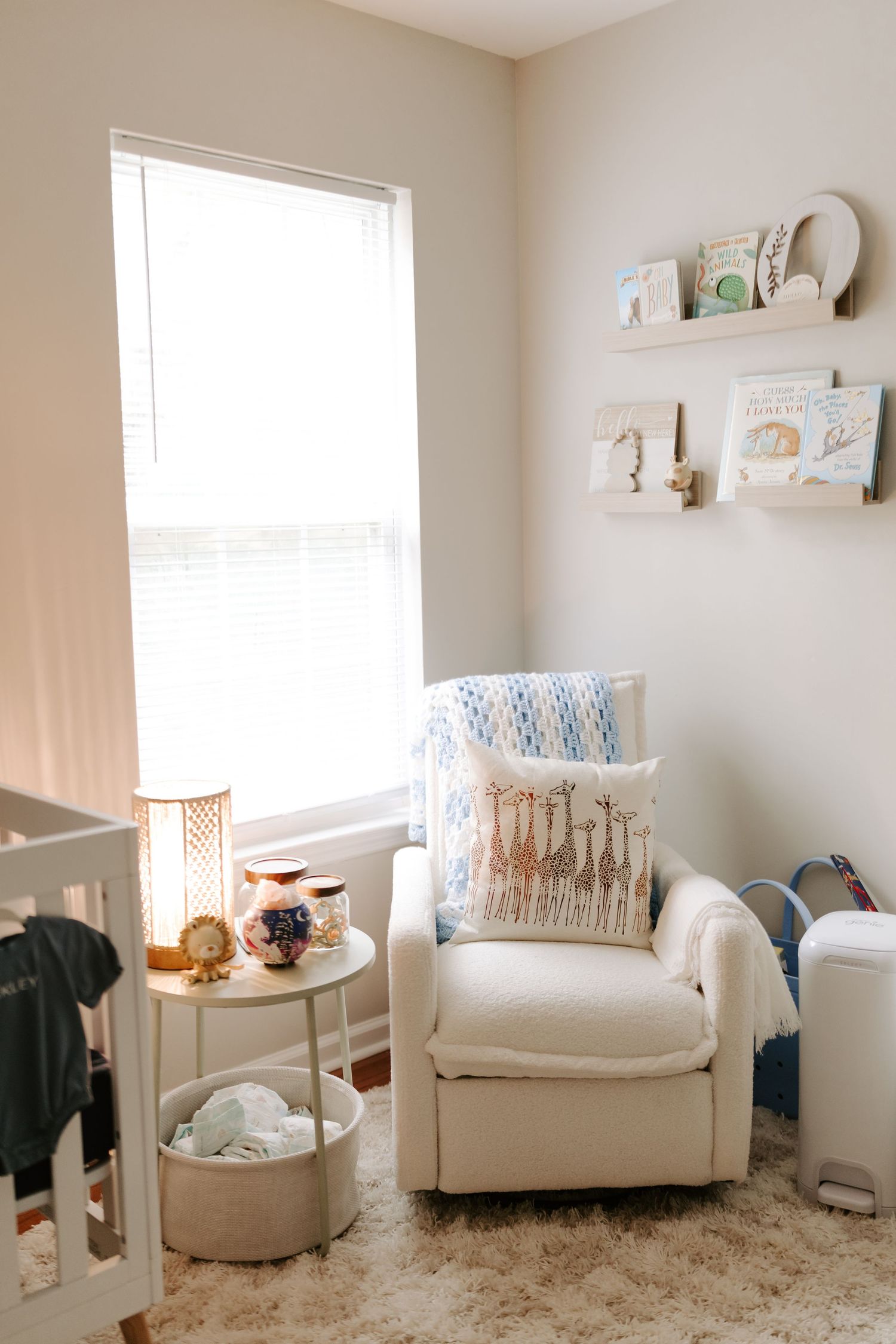 Cozy nursery corner with white armchair, floating shelves, and plush carpet.