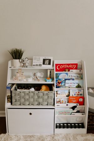 White bookshelf displaying children's books and decorative items in a nursery.