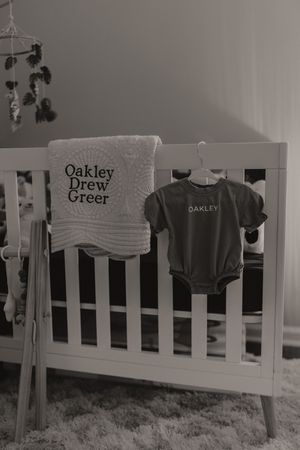 Gray and white nursery with personalized clothing and animal mobile above crib.