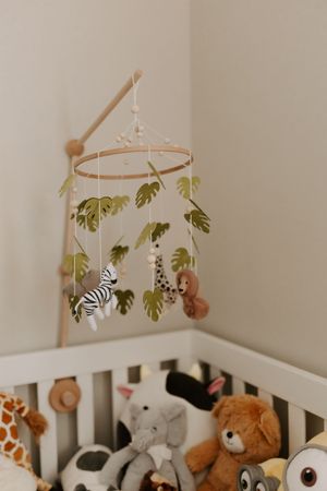 Safari-themed mobile with zebra and monkey plush toys hanging above white crib.