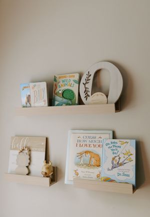 Children's books and decorative items displayed on floating wall shelves in a nursery.