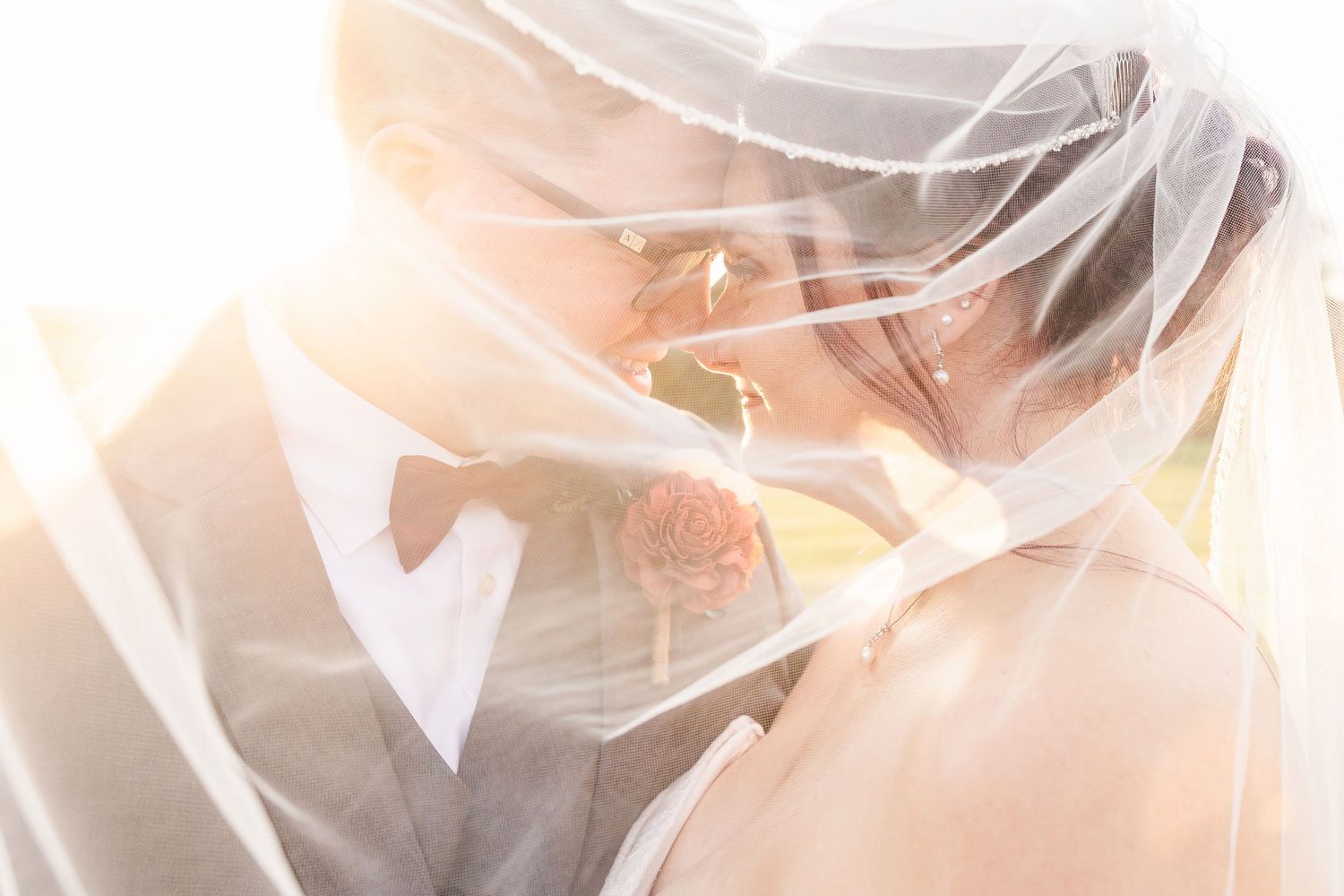 A romantic wedding scene with sunlight streaming through delicate white veil fabric creating an ethereal glow.