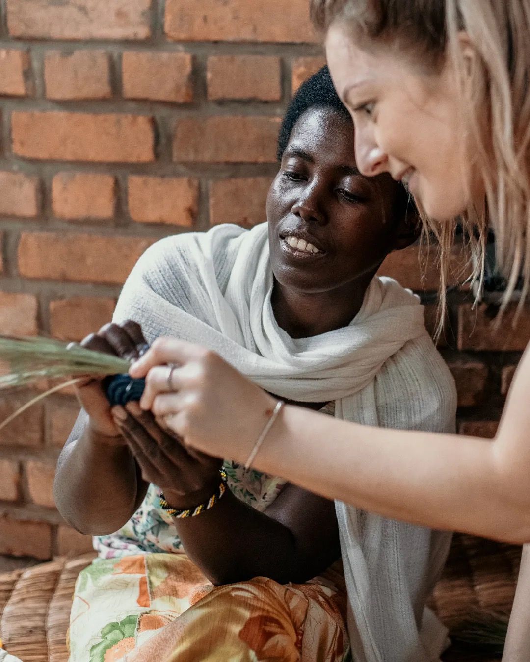 Woman helps another woman with sewing work, showing shared skills, support and community learning