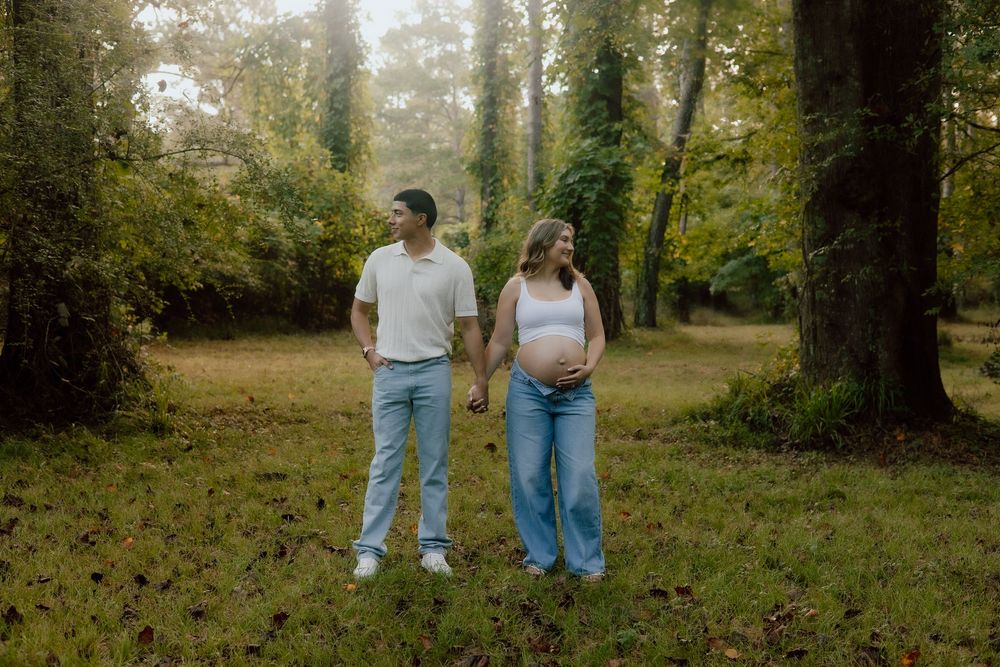Two people walk together through a lush wooded area on a sunny autumn day.