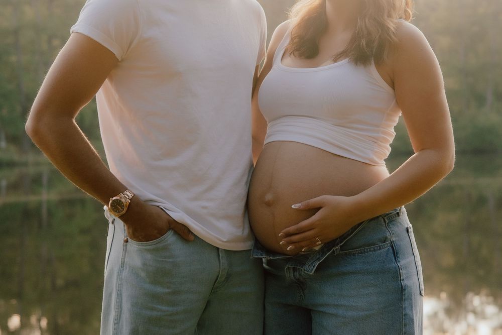 A series of intimate maternity photos showing a couple's belly in casual clothing against a soft outdoor backdrop at sunset.