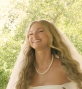 Bride in white dress with flowing hair captured in sunlit garden setting.