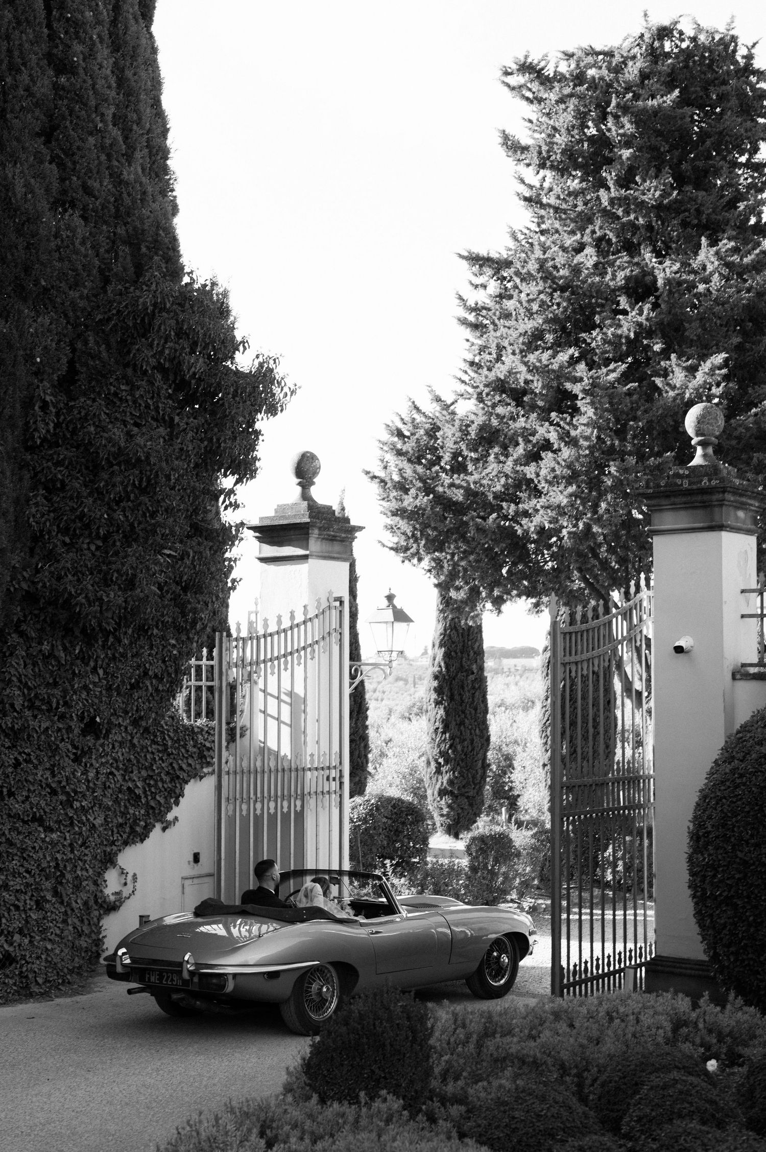 A happy couple rides in a classic convertible sports car after their wedding ceremony.