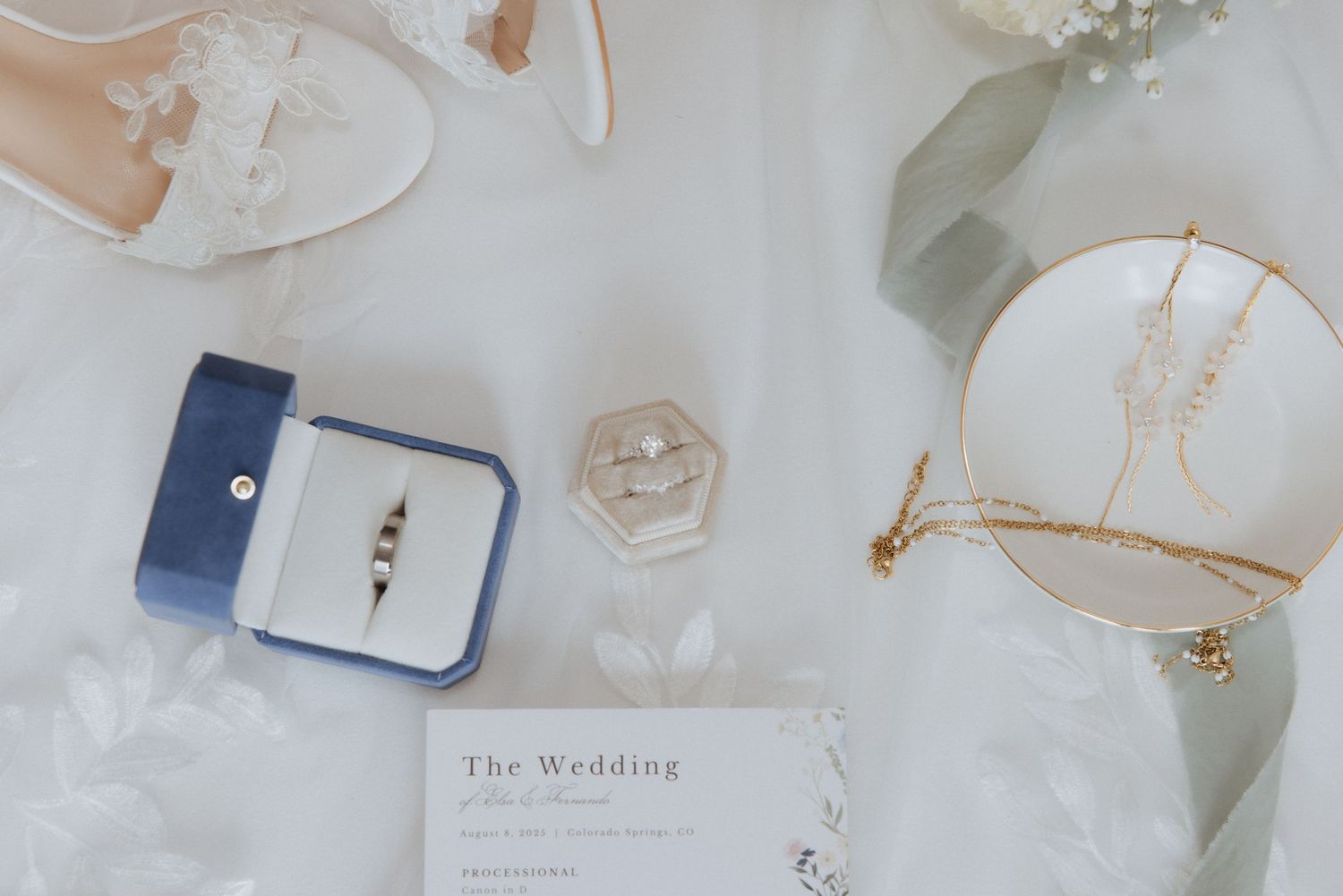 Elegant white wedding stationery and accessories arranged on light marble surface with delicate gold accents.