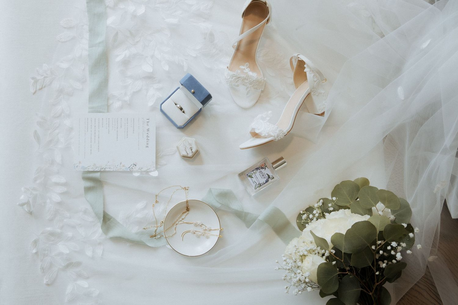 White and green floral wedding bouquet with delicate baby's breath accents rests on a light surface.