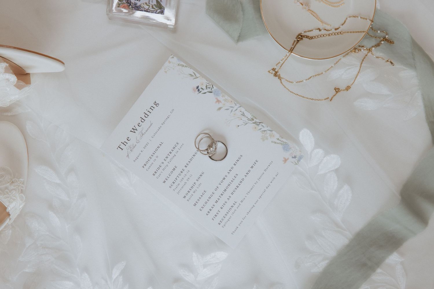 Wedding invitations and stationery with elegant floral designs and gold accents lay scattered on a white surface.