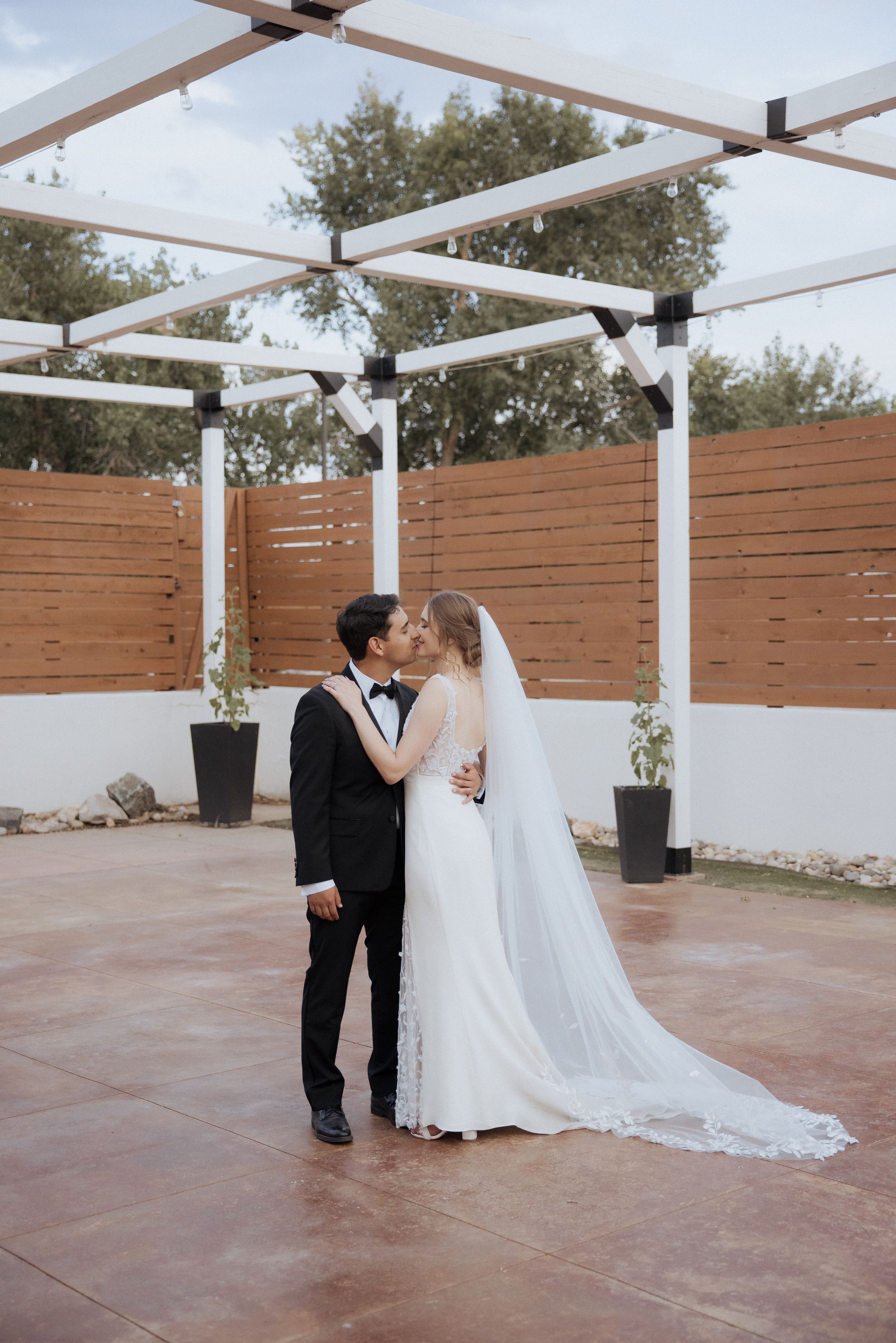 A series of romantic wedding photos showing a couple in formal attire sharing intimate moments under a white pergola.
