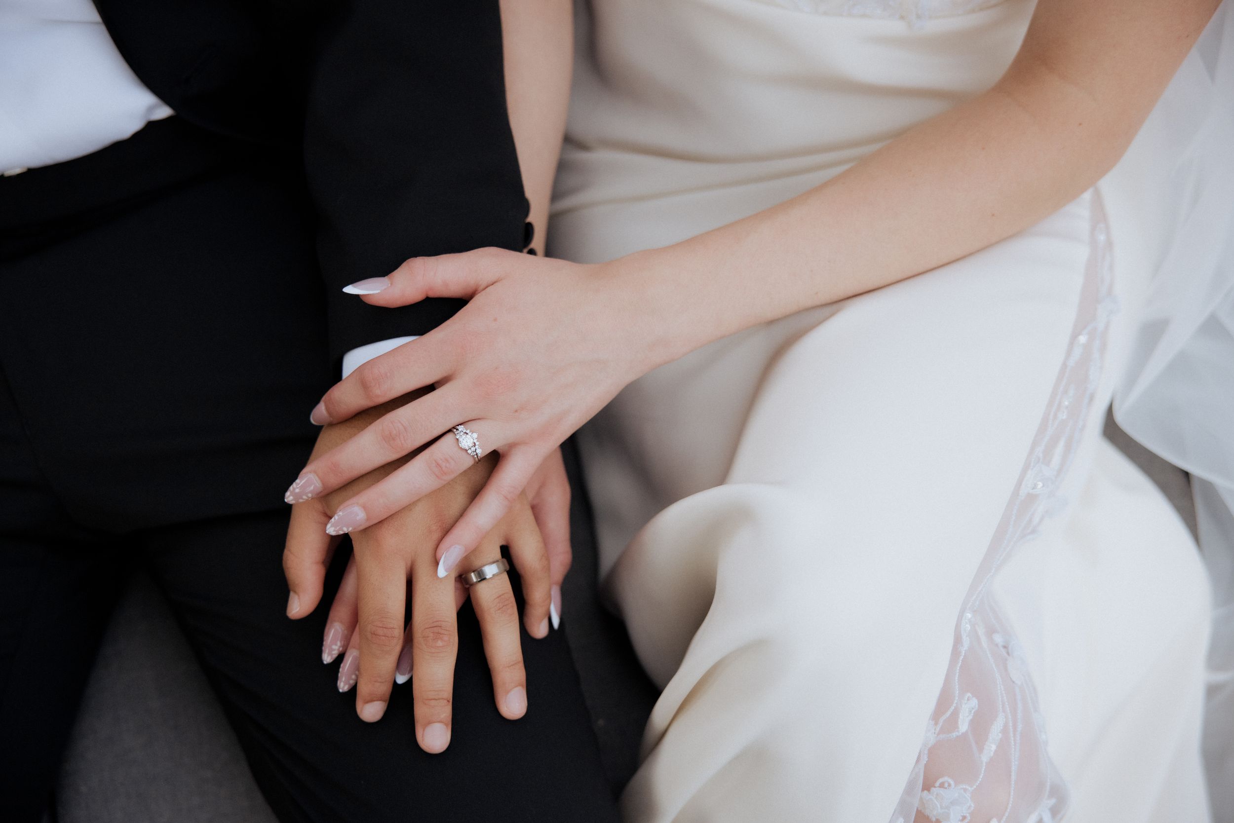 Close-up photos of hands showing wedding rings and details of a white wedding dress.