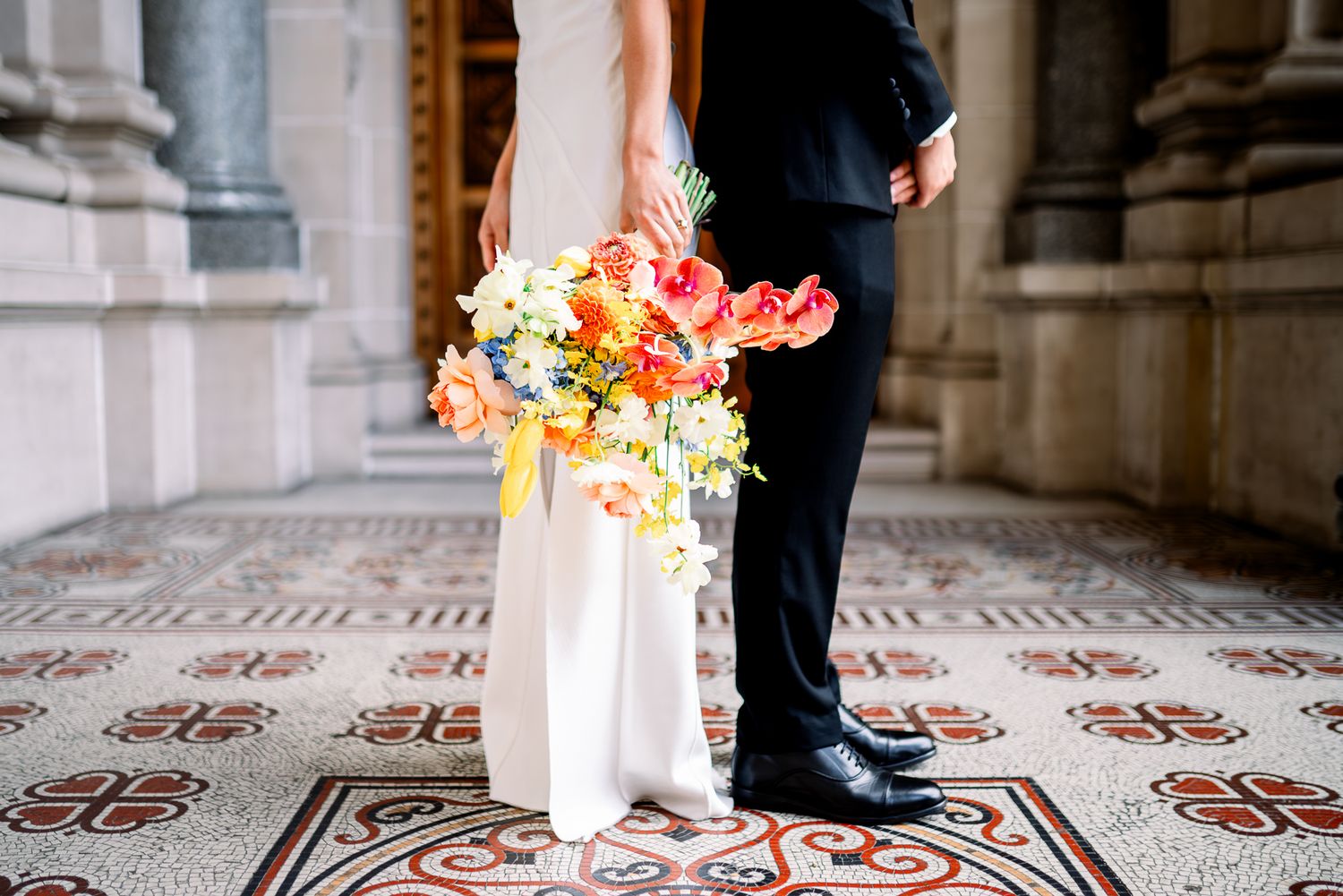 Newlywed couple shares intimate moments during their Melbourne wedding photoshoot against elegant stone pillars and columns.
