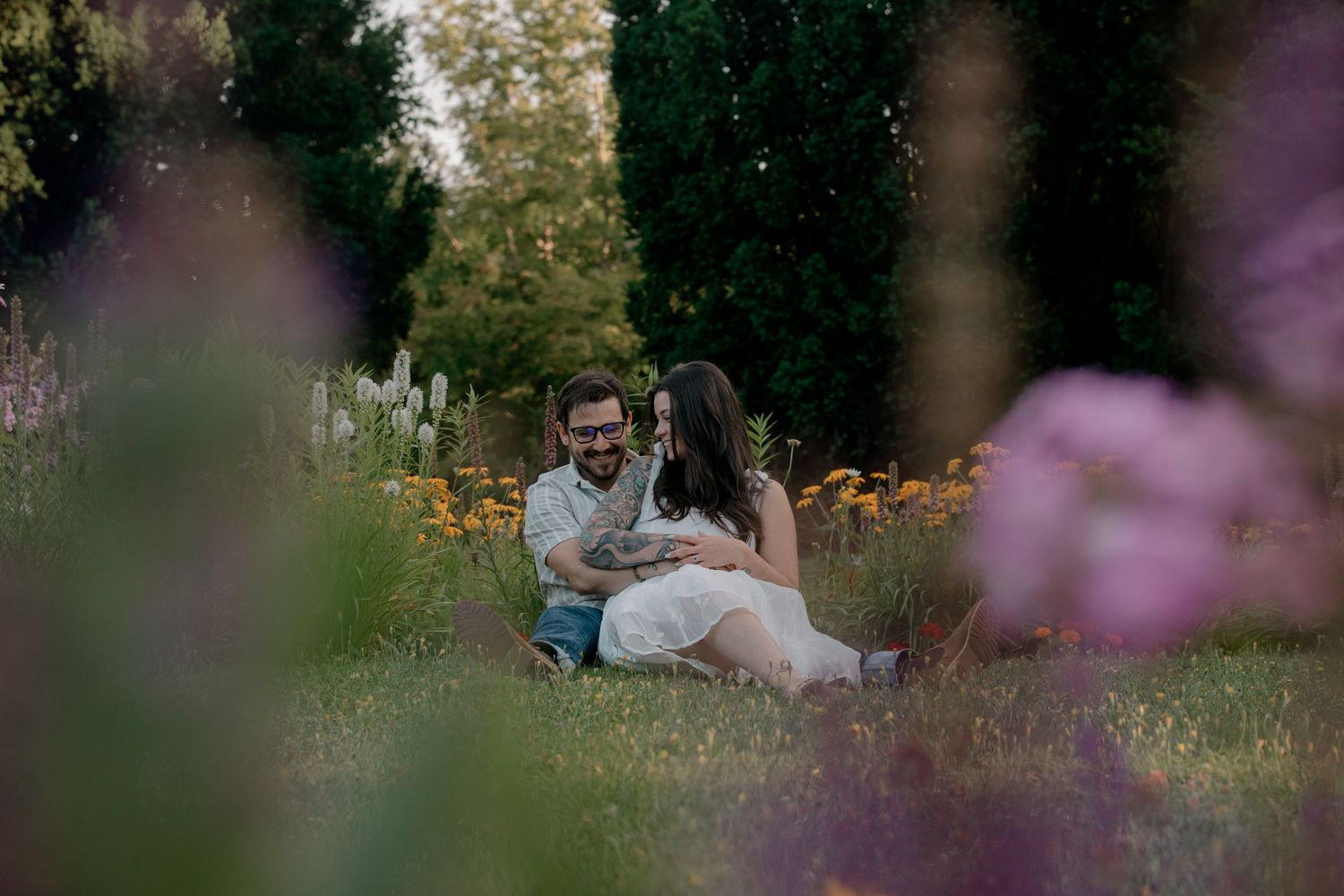 A romantic outdoor photo session in a garden with pink flowers and greenery in the foreground.