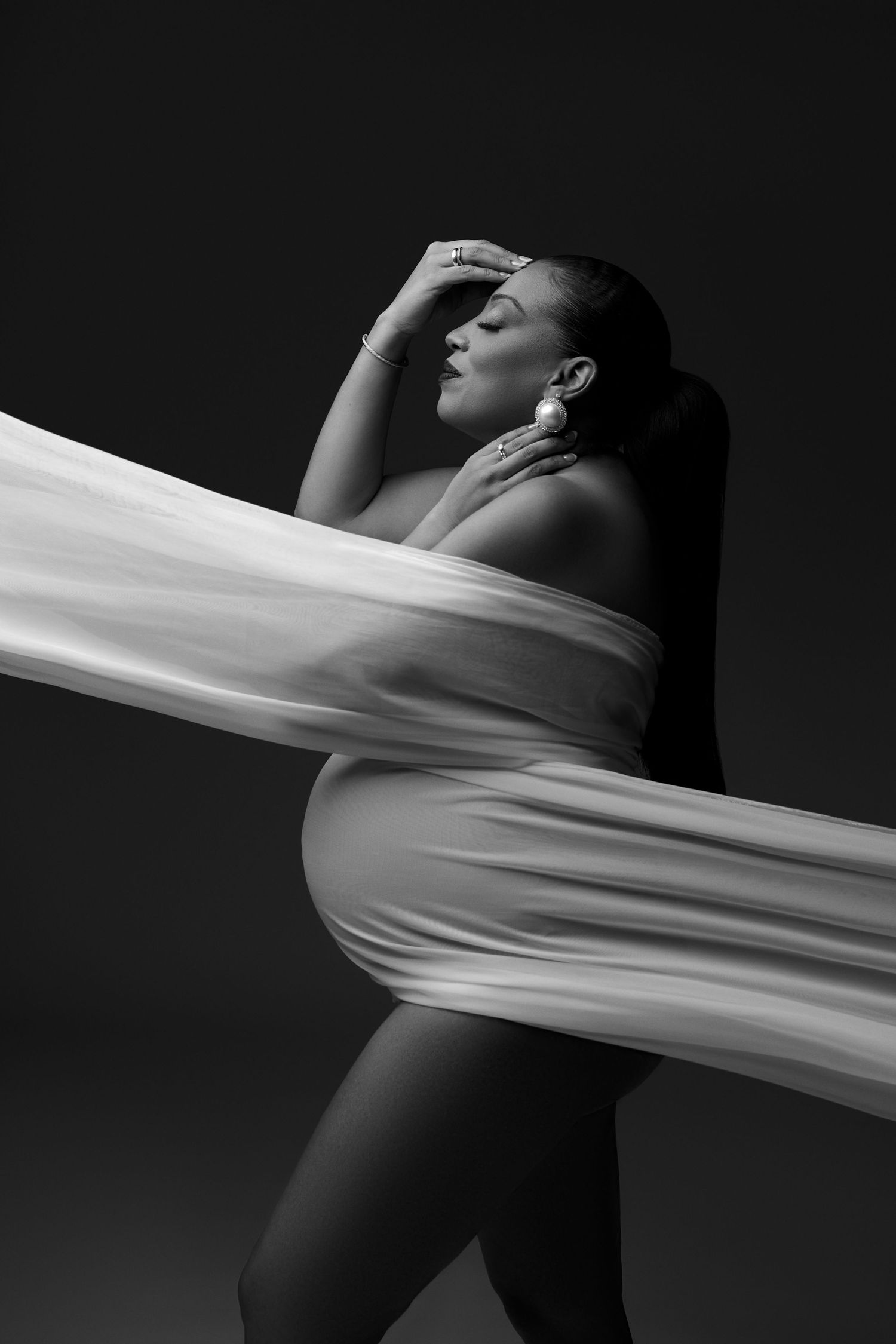 Dramatic black and white portraits featuring minimalist composition with flowing white fabric across dark space.