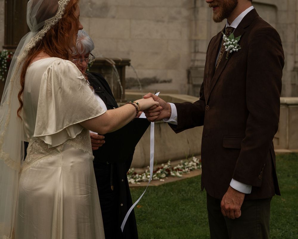 A couple in wedding attire shares a tender moment together during their outdoor ceremony.