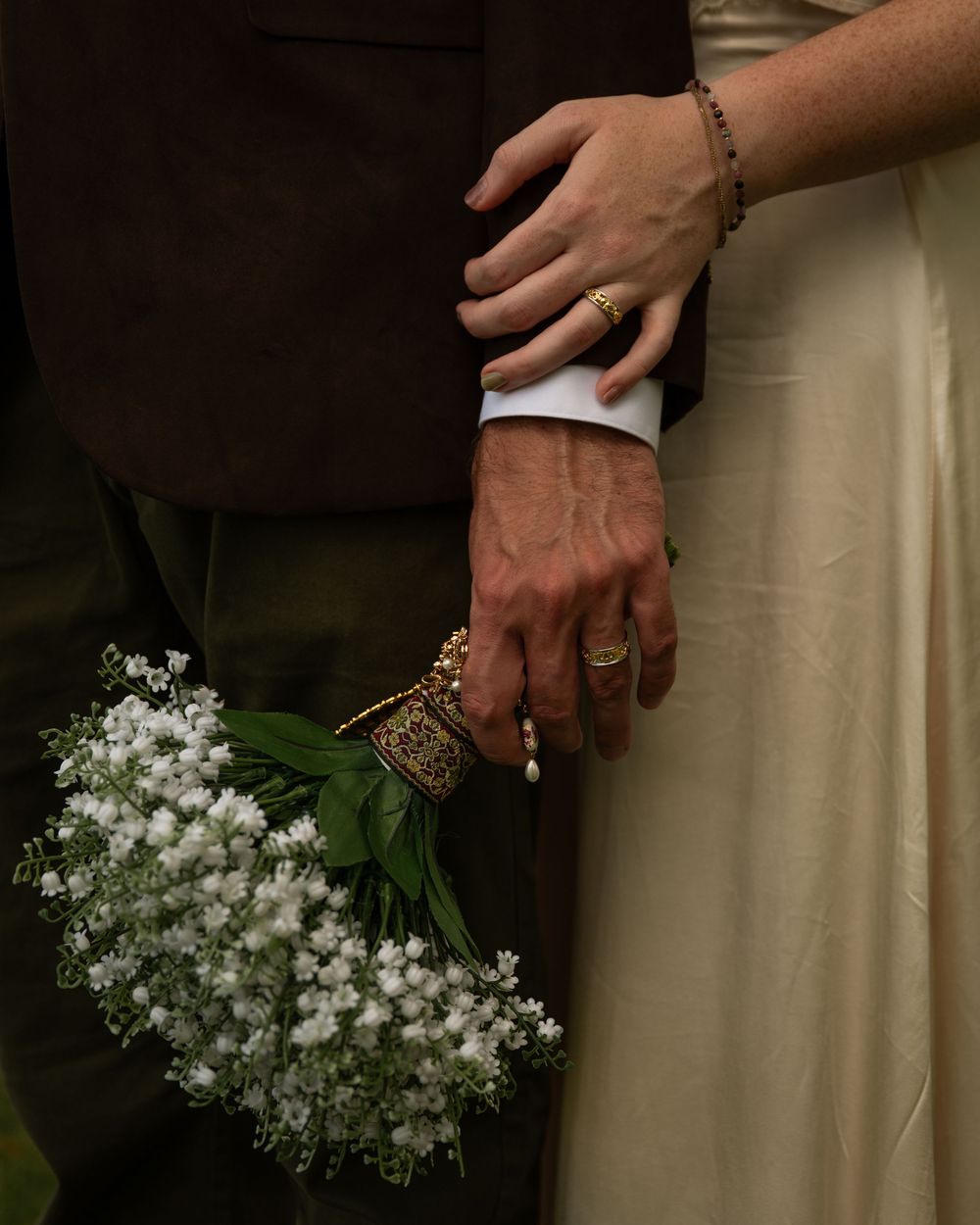 Close-up shots of hands holding delicate white baby's breath flowers against a light colored background.