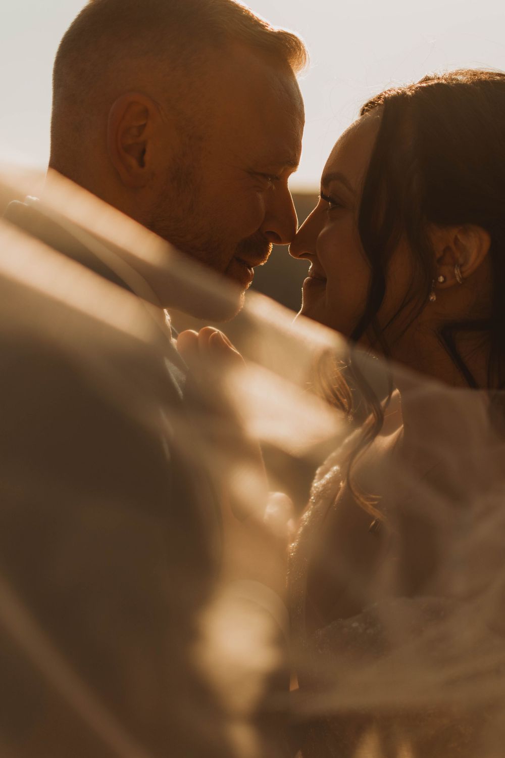 Romantic couple in intimate golden hour moment sharing tender embrace with soft sunlight filtering through.