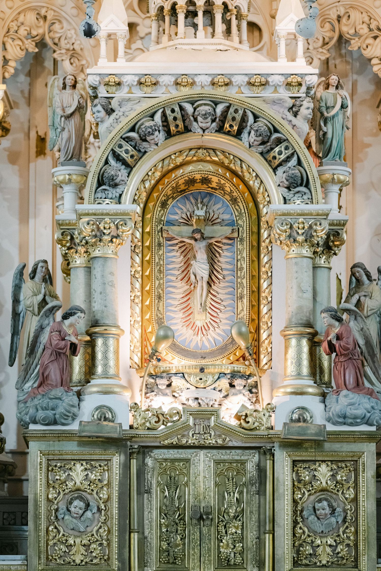 Interior view of ornate church with vaulted Gothic arches, stained glass windows and white painted architectural details.
