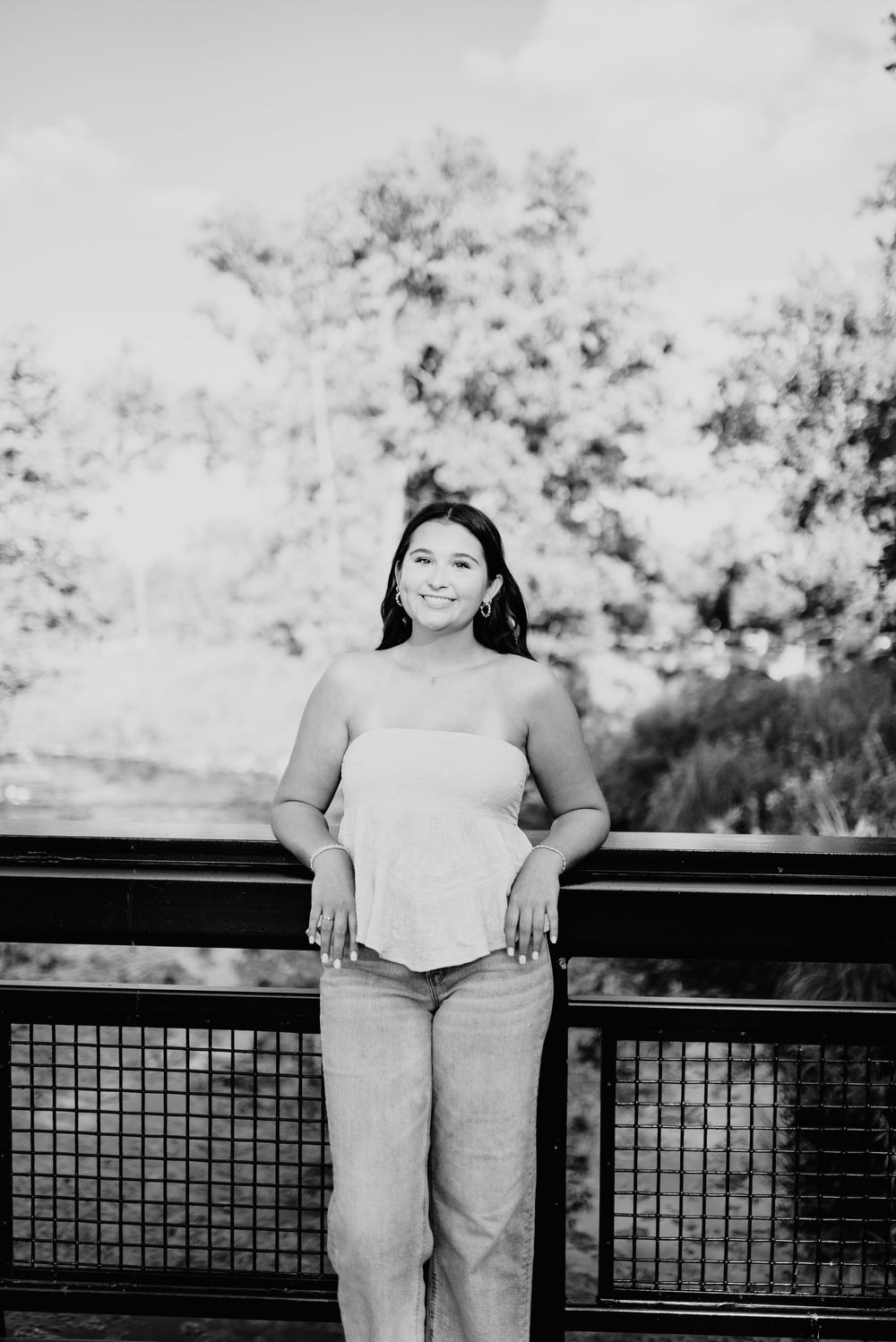 Black and white photo series showing a person in casual attire posing on an outdoor deck with railings and trees in background.