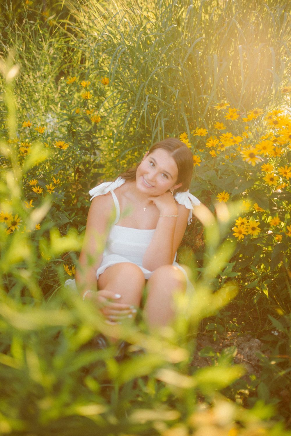 Maternity photo in a sunlit meadow with yellow wildflowers and soft natural lighting creating a dreamy atmosphere.