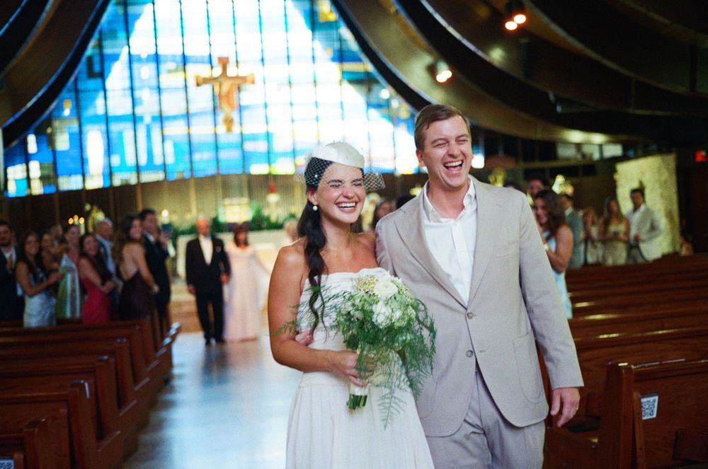 A happy couple walks down the aisle of a church after their wedding ceremony.