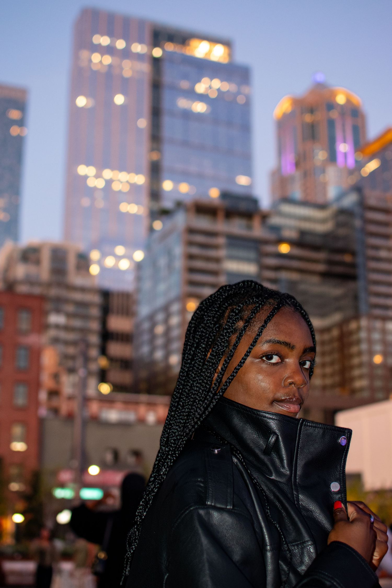 Black high school senior posing at the Seattle waterfront with glowing city lights during an evening portrait session.