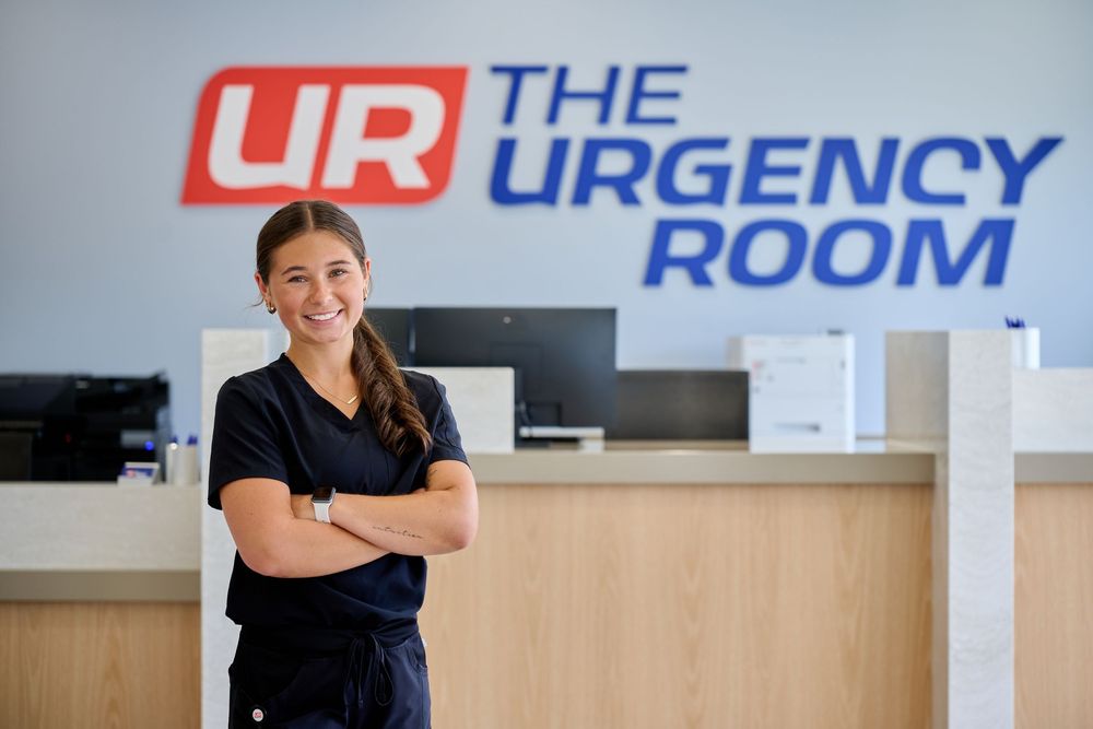 Medical professional in scrubs stands confidently in front of an emergency room sign at a hospital.