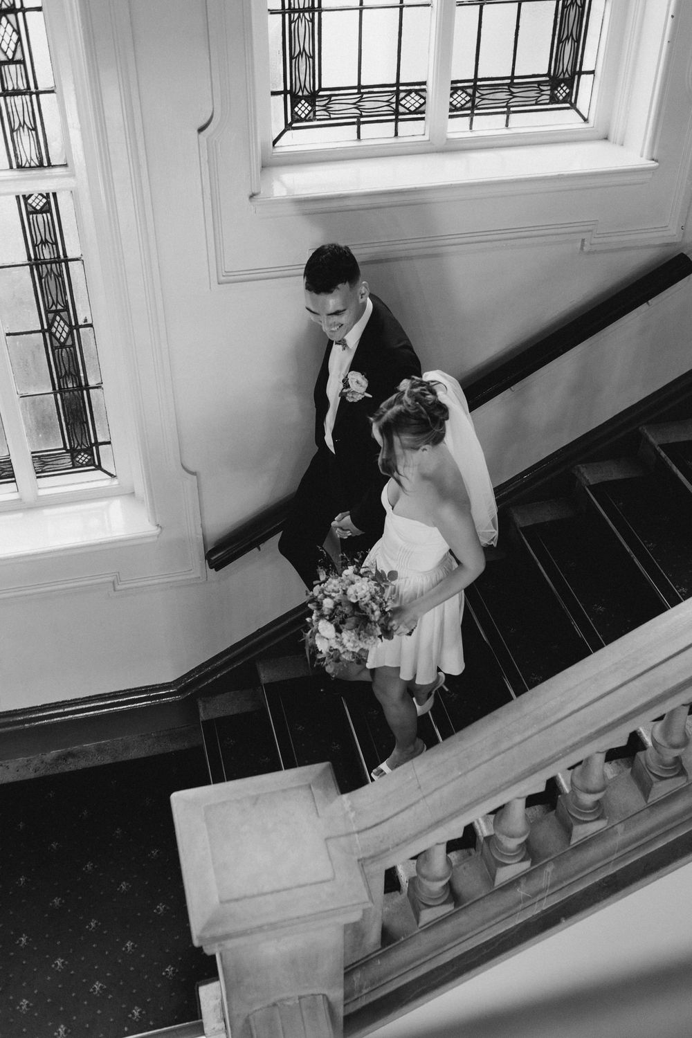 Artistic black and white sequence showing movement down elegant stairs with ornate railings.
